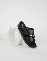 Black sandal with gold buckle on a white background