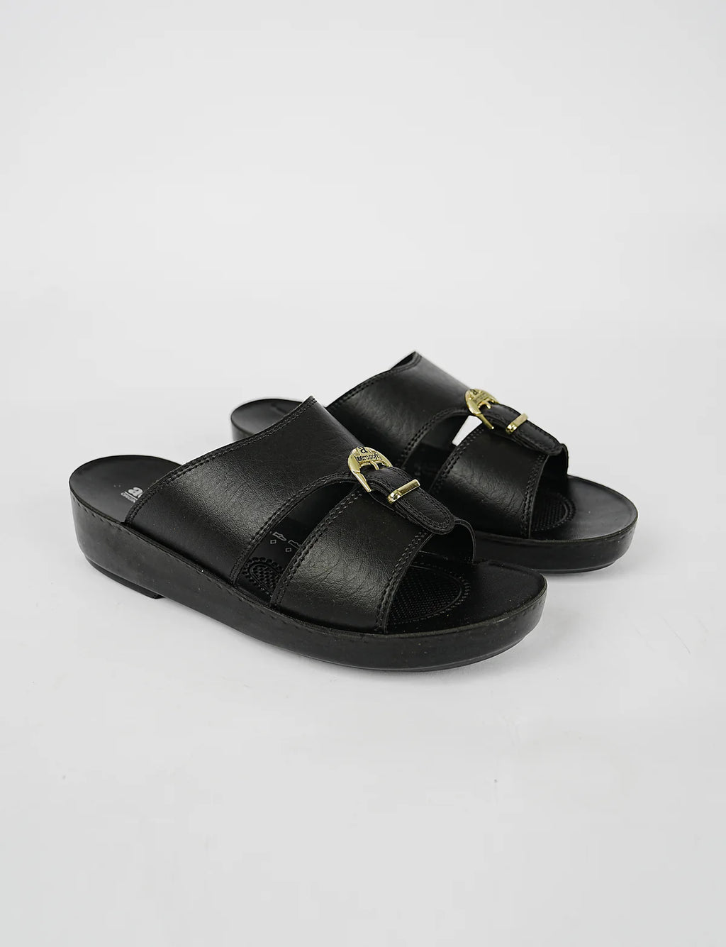 Black sandals with gold buckles on a light gray background