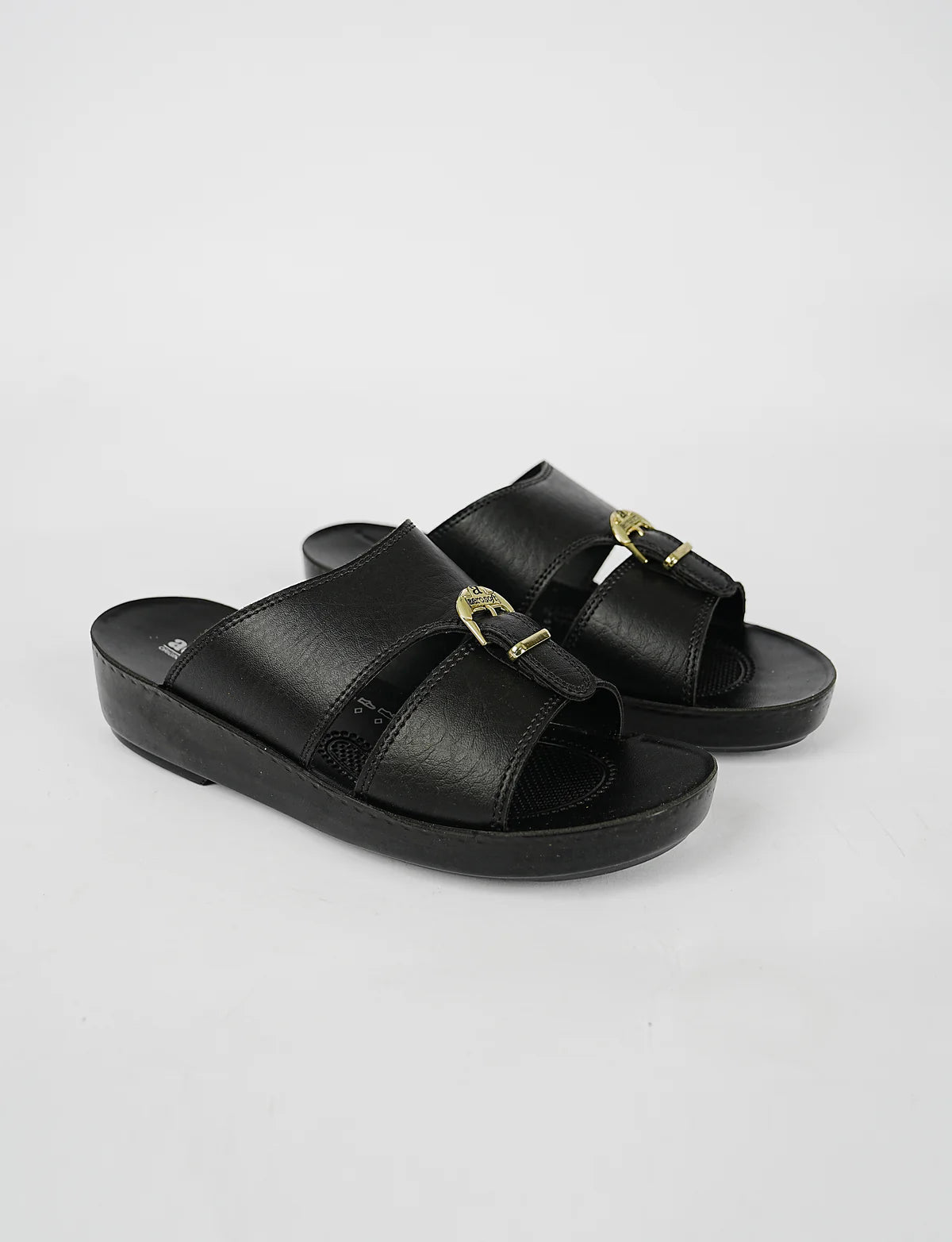Black sandals with gold buckles on a light gray background