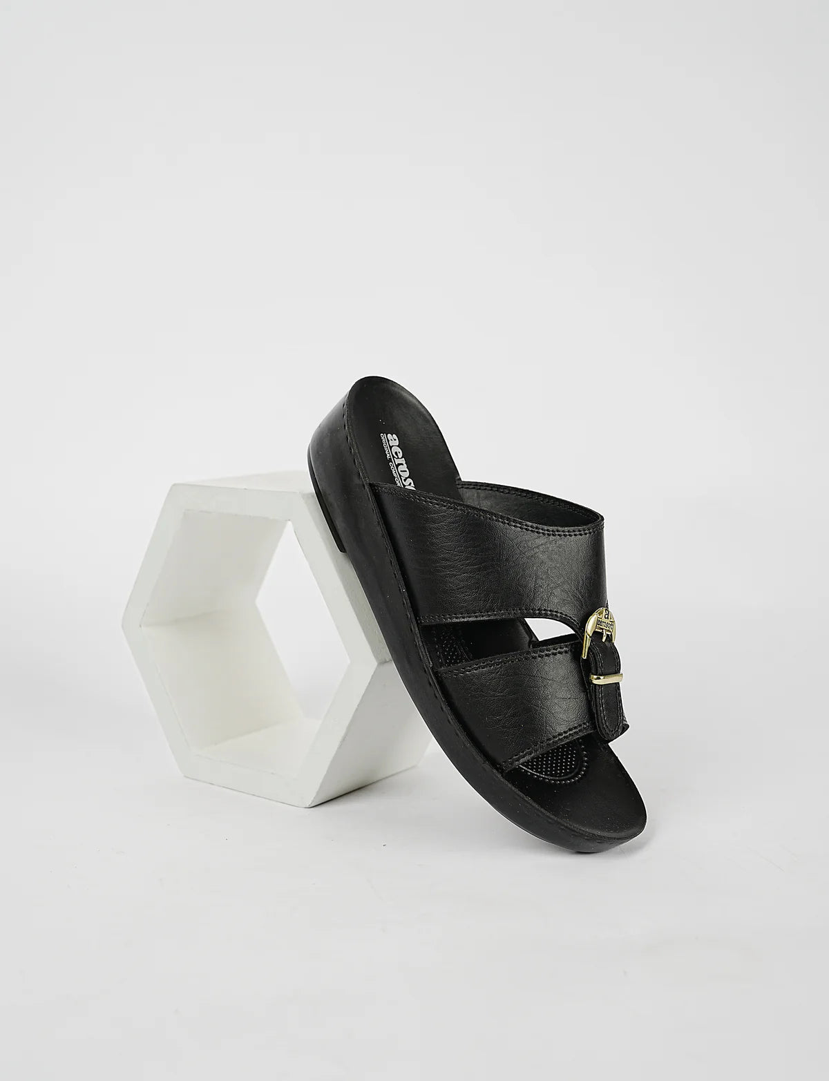 Black sandal with gold buckle on a white background