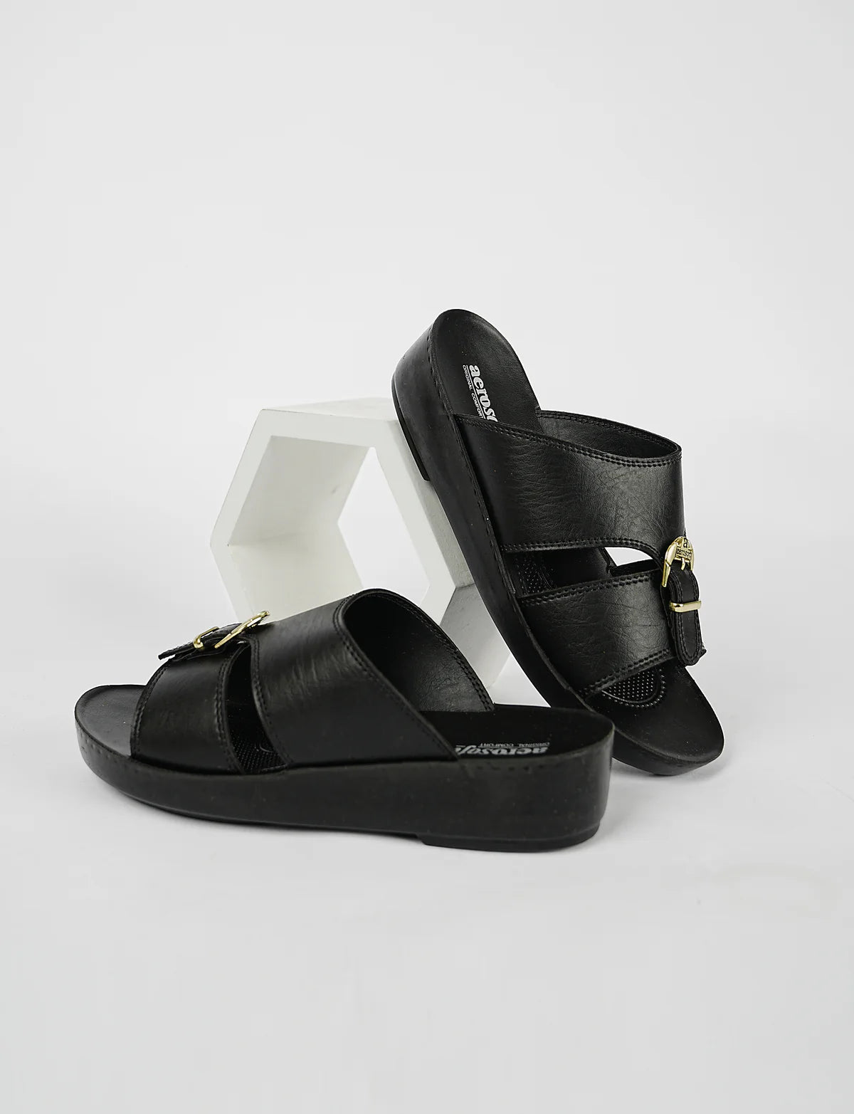 Black sandals with gold buckles on a white background