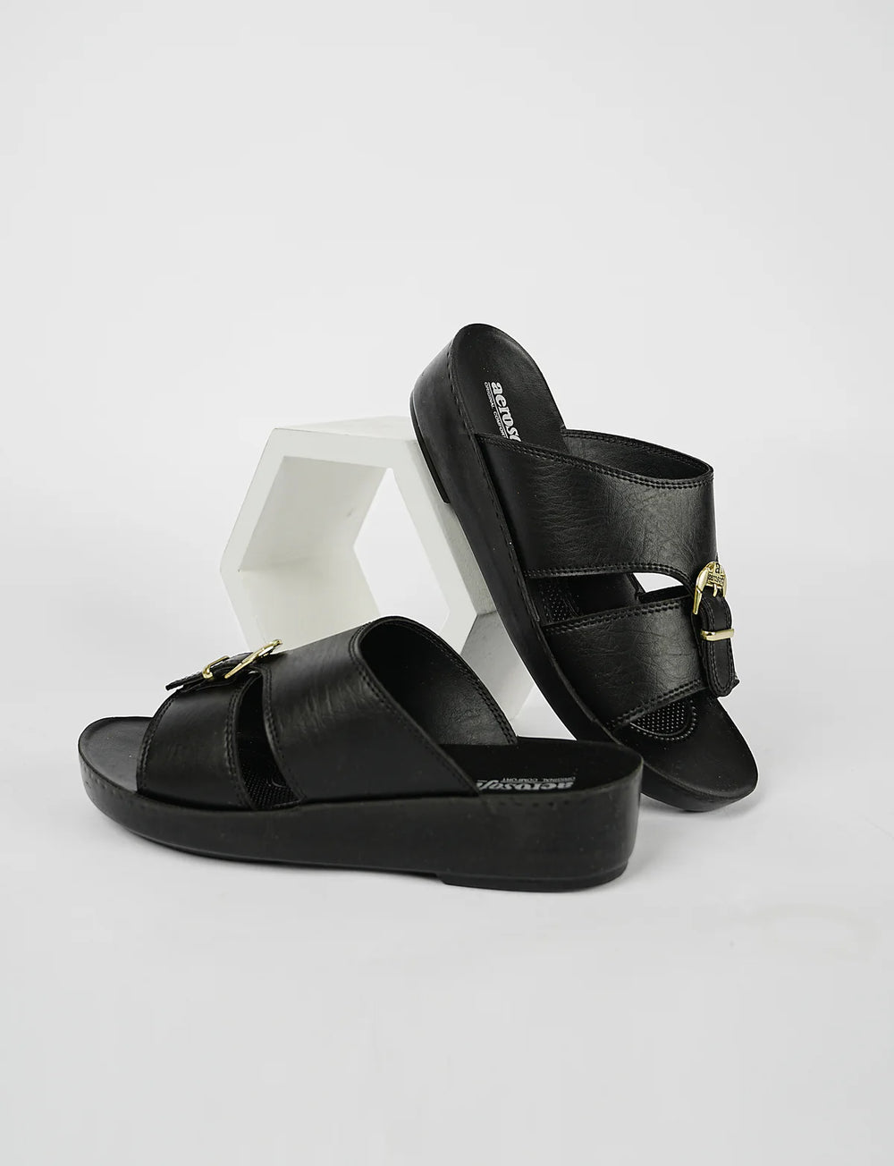 Black sandals with gold buckles on a white background